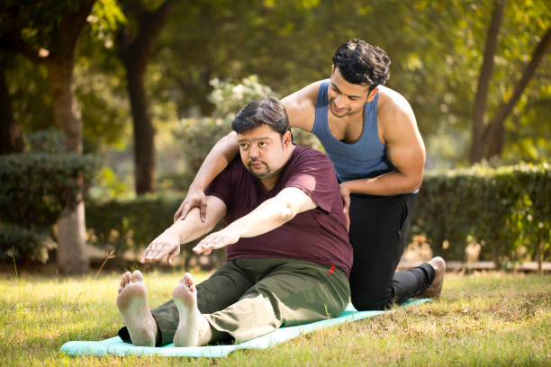 personal-trainer-motivating-overweight-man-doing-exercise-at-park.jpg